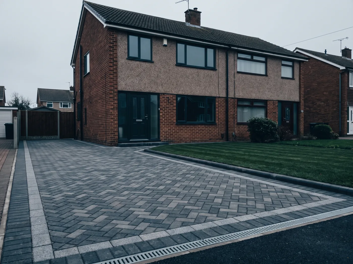 The same house with a new charcoal and grey herringbone block driveway, sett border and drainage channel