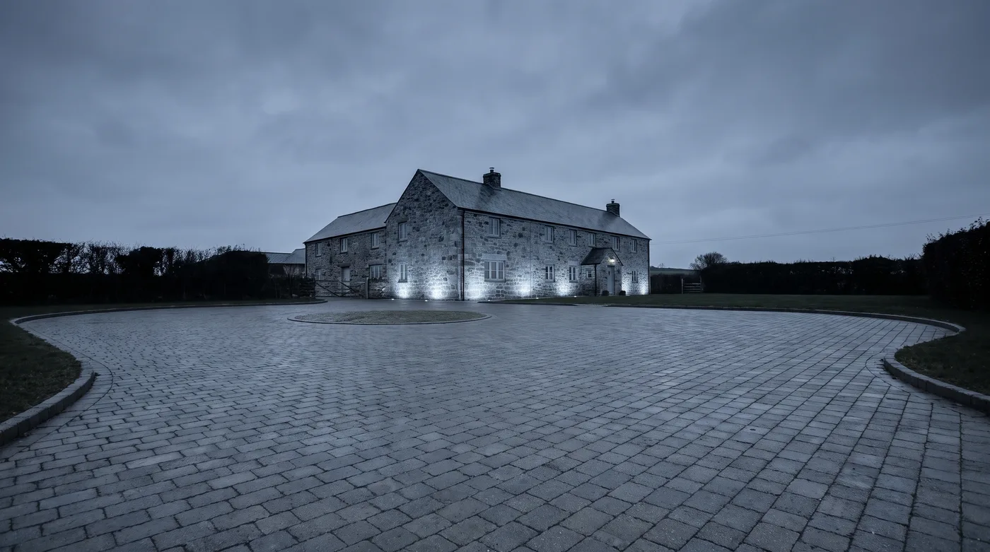 Completed paved driveway at dusk with warm light from the house