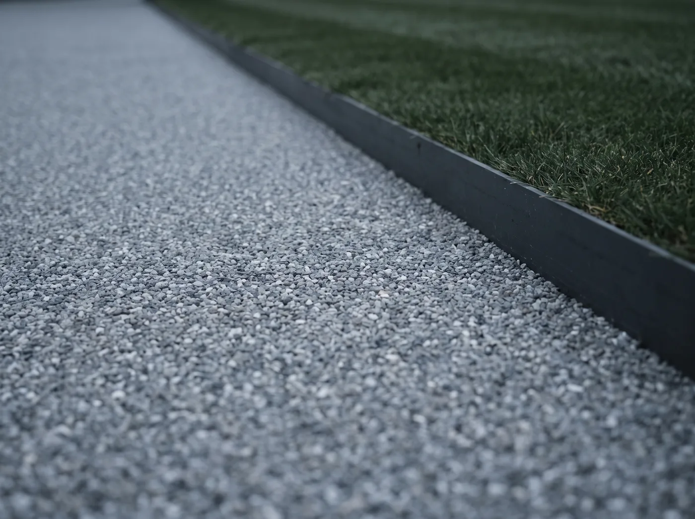 Seamless grey resin-bound driveway surface meeting a charcoal steel edging strip